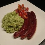 Tre korvar på en vit tallrik med grön puré och hackade tomater.