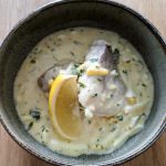Skål med fiskfilé i krämig sås med citron och örter.
