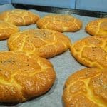 Nygräddade Oopsies bröd på en plåt med bakpapper, toppade med sesamfrön.