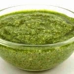 Grön pesto i en genomskinlig skål med en slät konsistens.