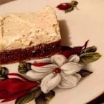 En bit cheesecake med en mörk botten på en tallrik med blommönster.