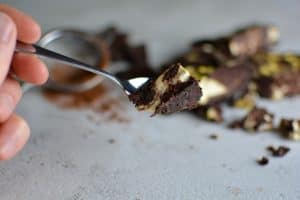 En sked med en bit cheesecake brownie som har en mörk choklad- och ostfyllning.