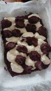 En bakad chokladkaka med gräddfyllning i en fyrkantig form, dekorerad med mörk choklad.