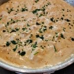 En panna med köttbullar i en krämig sås, toppad med hackad persilja.