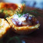 Minivästerbottenpaj med lök och dill på en träyta.