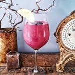 Ett glas med bärsmoothie dekorerat med en citronskiva och blåbär.