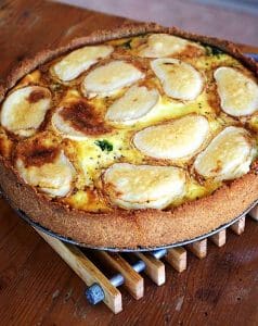 Spenat- och getostpaj med skivor av potatis på toppen, gräddad i en rund form.