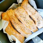 Fyra laxfiléer som tillagas i en airfryer med bakplåtspapper.