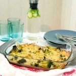 En bacon och broccoligratäng i en glasform, med grönsaker och ost på toppen.