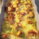 Vitkålsgratäng med bitar av kyckling och bacon täckt av smält ost i en ugnsform.