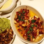 Rätt med torskfiléer toppade med soltorkade tomater, bacon och grönsaker i en ugnsform.
