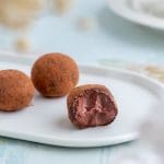 Tre chokladtryfflar på en vit tallrik, varav en är delad för att visa insidan.