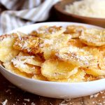 En skål med gyllenbruna parmesanäggchips som är strödda med riven parmesan.