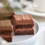 Tre bitar av chokladkaka med chokladfrosting på en vit tallrik.