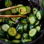 Skål med skivade gurkor i en asiatisk dressing, med ätpinnar placerade ovanpå.