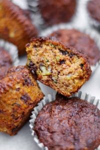 Zucchinimuffins med en bit av en muffin som visar inuti med chokladbitar.
