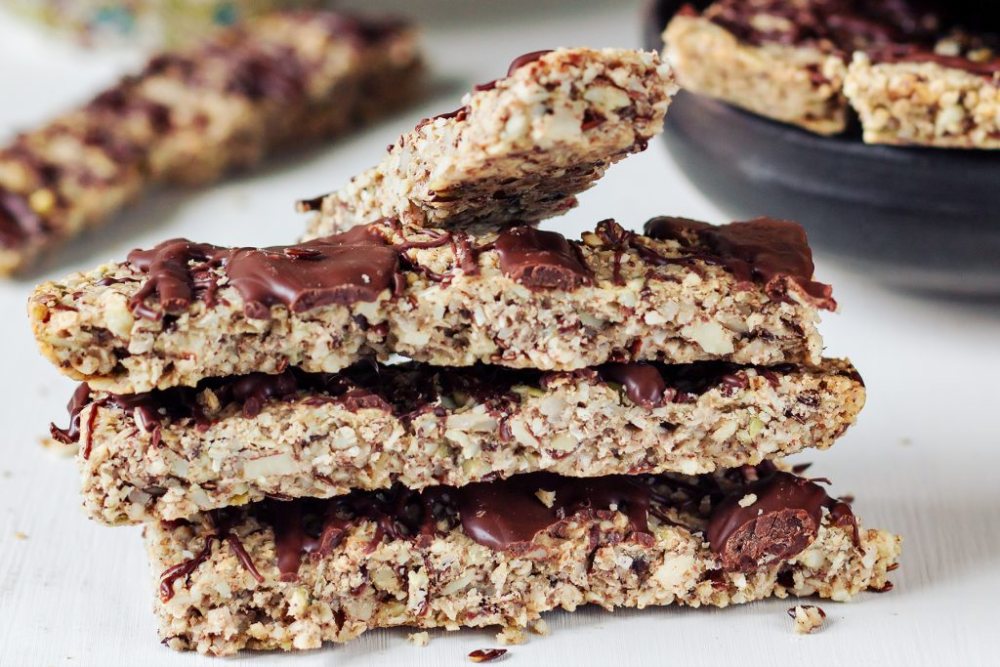 Stapel av hemgjorda fröbars med choklad på toppen, med en mörk bakgrund. Stapel av hemgjorda fröbars med choklad på toppen, med en mörk bakgrund.