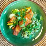 En tallrik med grillad lax, grönsaker och couscous på en grön tallrik.