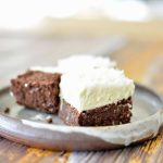 Två bitar av kaka med chokladbotten och kokosfrosting på en tallrik.