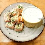 Tärnad lax serverad med en skål med sås och dill på en tallrik.