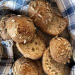 Bröd med solrosfrön, delvis skurna, placerade i en blå och vit rutig handduk.