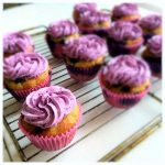 Cupcakes med gul bas och lila frosting placerade på ett galler.