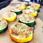 Grillad zucchini och squash skivor med brödsmulor på en plåt med bakpapper.